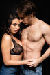© LIGHTFIELD STUDIOS - sexy woman in lace bra holding hands with shirtless man isolated on black.