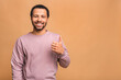 © denis_vermenko - Portrait of a cheerful smiling young afro american black man dressed in casual isolated against beige background, showing thumbs up.