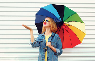 Wall Mural - Portrait of happy smiling young woman with colorful umbrella on a white background