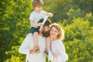 Sticker - Happy family - father mother and child on meadow with a toy paper airplane in the summer on the nature background. Parenthood. Family like summer time together.