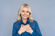 © insta_photos - Happy smiling mature 50 years old woman looking at camera feeling sincere gratitude. Portrait of grateful mindful woman prayer hands on chest isolated on grey background. Mental health care concept.