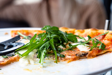 Wall Mural - Pizza with arugula and burata is on a plate in a restaurant.