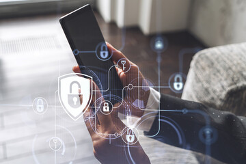 A woman programmer is browsing the Internet in smart phone to protect a cyber security from hacker attacks and save clients confidential data. Padlock Hologram icons over the typing hands. Formal wear