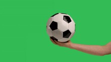 Female Hand Holds A Football Classic White Black Ball On The Palm, Isolated On Green Screen Chroma Key Background. Sport Play Football Healthy Lifestyle Concept. Slow Motion. Close Up.