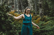 Woman in linen emerald jumpsuit, wearing glasses, walking merrily in a park