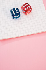 Sticker - Closeup shot of two rolling dices on a notebook isolated on a pink background