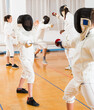 © JackF - Portrait of kids and adults fencers with instructor engaged in fencing in training room