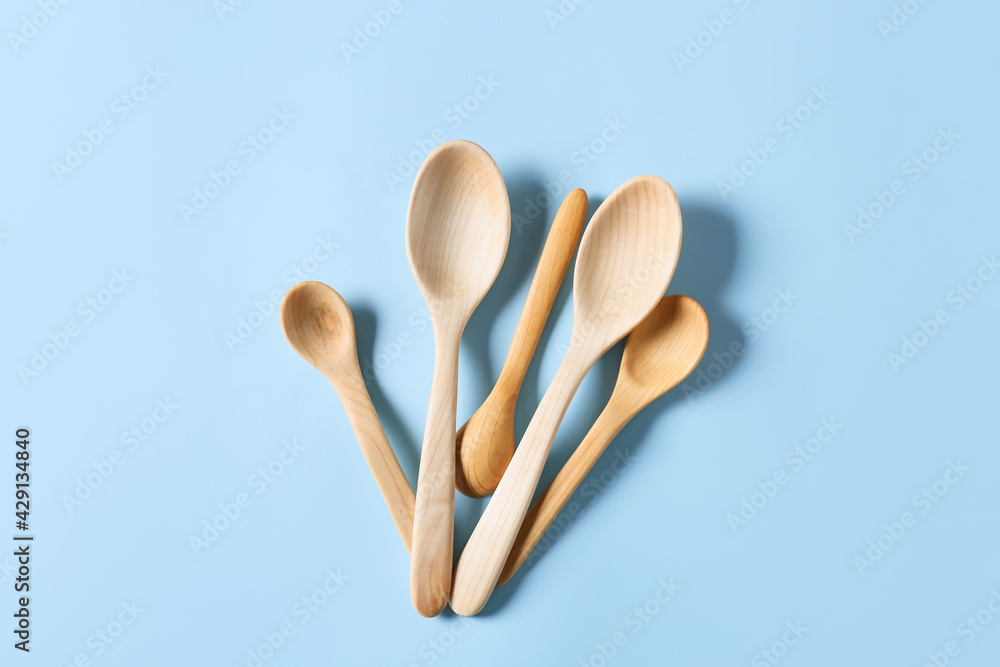 Different wooden spoons on color background