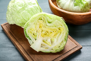 Board with iceberg lettuce on color wooden background, closeup