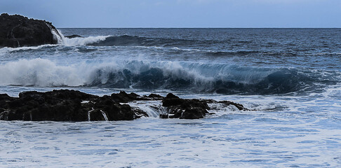 Poster - Beautiful view of a rocky, wavy sea or lake in a blue sky background