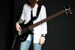© Volha - a girl guitarist stands with an electric guitar on a dark background.