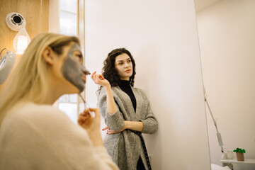 Two girls playing with cosmetic SPA mask on their faces. Little girl and young woman enjoy spa treatments. SPA and wellness.