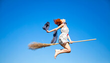 Young Red-haired Witch On Broom Flying In The Sky
