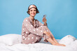 © deagreez - Full body profile side photo of positive brown bob haired lady sit blanket hold smartphone sleepover isolated on blue color background