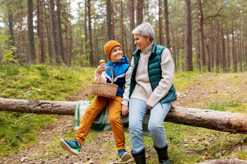 Canvas Print - picking season, leisure and people concept - happy smiling grandmother and grandson with baskets and mushrooms in forest