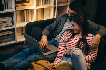 Wall Mural - couple using laptop computer sitting on a sofa at home