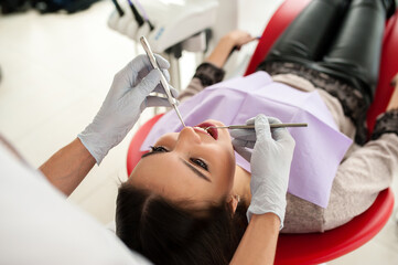 Wall Mural - Adult male dentist treating patient woman teeth. Medicine, dentistry and healthcare concept.