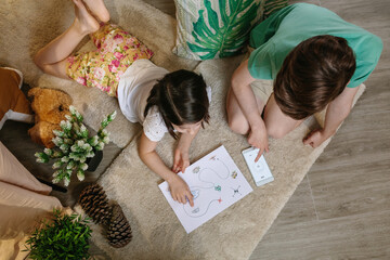 Top view of unrecognizable children playing treasure hunt at home on the carpet