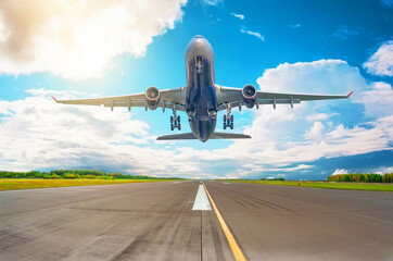 Rapidly plane taking off runway, airstrip with marking on blue sky with clouds background. Travel aviation concept