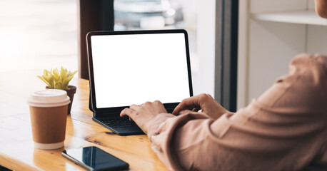 Cropped shot of young professional businesswoman typing on blank screen tablet and office supplies in simple workspace.