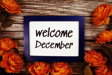 Poster - Welcome December text in blue border frame with flower decoration on wooden background