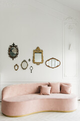 Stylish modern interior of the bright living room with a semi-circular pink sofa and vintage mirrors