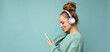 Panoramic Side-ptofile closeup photo of beautiful young woman wearing stylish casual outfit isolated over colorful background wall wearing white wireless headphones and listening to music and using