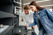 © fotofabrika - Young couple choosing new electric oven in hypermarket
