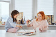 © boytsov - Art creative leisure activity. Beautiful caring art teacher or painter helps to draw cute preschool girl sitting at the table using watercolor, teacher enjoy helping small kid doing painting at home