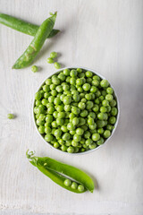 Wall Mural - Bowl with fresh peas on a wooden background. Green peas in white bowl.