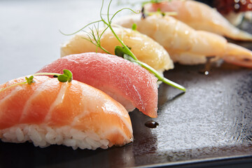 Canvas Print - Japanese Nigiri Sushi Set - Sushi with Rice and Various Seafood. Salmon, Tuna, Sea Scallop and other seafood fish. Nigiri Sushi row on black slate platter. Isolated on white background.