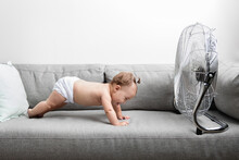 Funny Baby Doing Pushups On Couch In Front Of Electric Fan