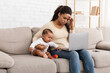 © Prostock-studio - African Mom Hugging Crying Sick Baby Using Laptop At Home