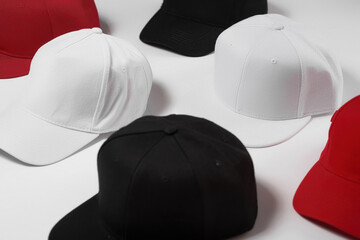 Wall Mural - Closeup shot of many baseball snapback hats in different colors black, white and red laid out on white surface