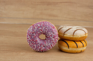 Poster - colorful donuts or doughnut on wooden table background.