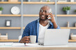 © Prostock-studio - Coffee break. Happy african american employee talking on cellphone and holding cup with hot drink