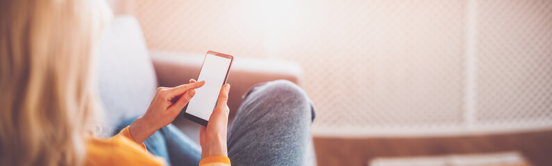 Young woman on the couch using her smartphone.