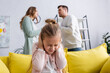 © LIGHTFIELD STUDIOS - Girl covering ears near parents quarrelling at home.