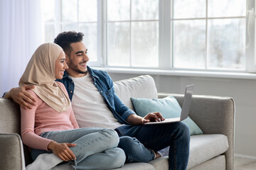 Wall Mural - Happy young muslim family using laptop together at home