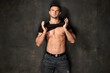 Sexy sport muscle strongface guy  in denim blue jeans and black t-shirt on black wall background