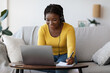 © Prostock-studio - Smiling black lady in headset writing notes while watching webinar on laptop