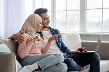 Wall Mural - Young muslim family making purchases on Internet via laptop