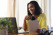 © Wavebreak Media - Happy mixed race transgender woman making video call using laptop, smiling, holding notes