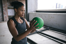 Determined Fit African American Woman Exercising Holding Volleyball Ball In Empty Warehouse Space