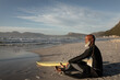 © Wavebreak Media - African american senior man on beach sitting with surfboard looking out to sea