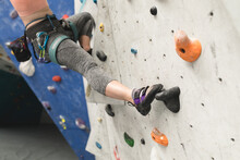 Mid Section Of Caucasian Woman Climbing Up A Wall At Indoor Climbing Gym