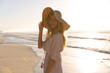 © Wavebreak Media - Caucasian woman wearing beach cover up and hat having fun at the beach