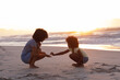 © Wavebreak Media - African american mother and daughter collecting shells at the beach smiling