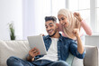 © Prostock-studio - Happy arab couple with digital tablet raising fists up