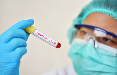 Wall Mural - Lab technician holding blood sample tube positive with COVID-19 virus